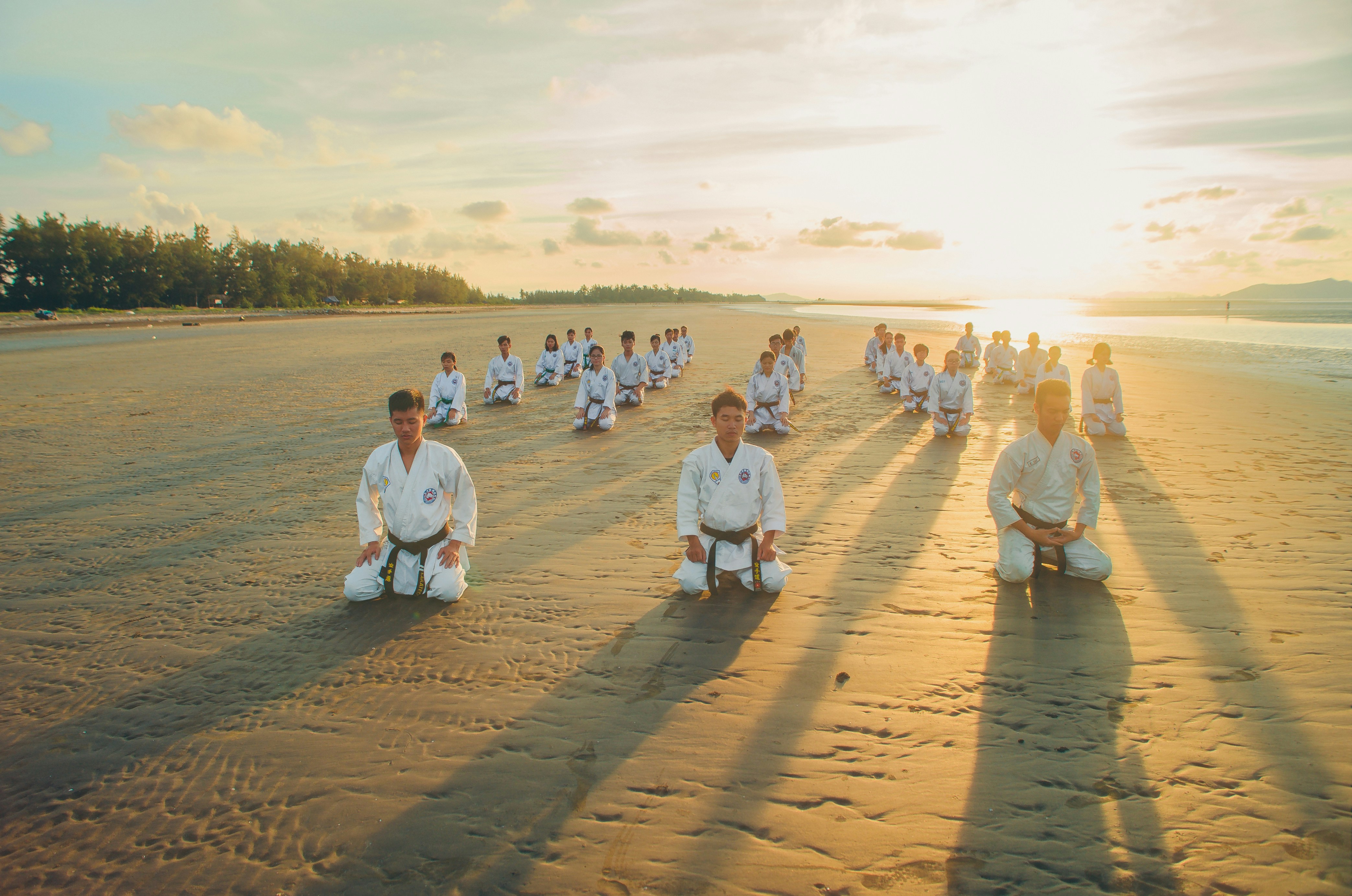 Practitioners gathered on a beach at sunset, reflecting the Fire element and Heart season of summer in Chinese medicine